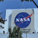 Workers install a massive NASA sign at Jet Propulsion Laboratory, which later saw layoffs of more than 500 employees in cost-cutting.